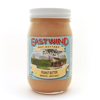 A 16 ounce glass jar of East Wind Nut Butters' Valencia peanut butter, smooth with salt.